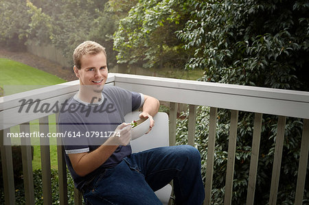 Young man having salad on balcony