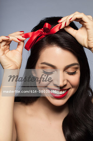 Mid adult woman tying red ribbon in hair - Stock Photo - Masterfile -  Premium Royalty-Free, Code: 614-08030695