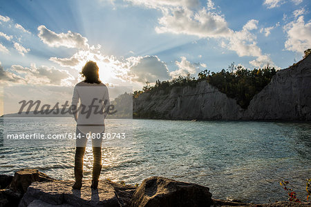 Mid adult woman on rocks, Scarborough Bluffs, Toronto, Canada