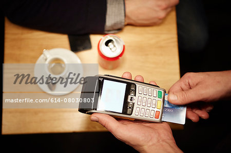 Restaurant worker inserting customer's credit card into credit card reader