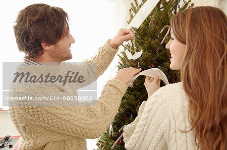 Young couple putting decorations on christmas tree