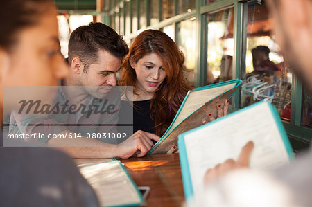 Four friends looking at menus in vegetarian restaurant