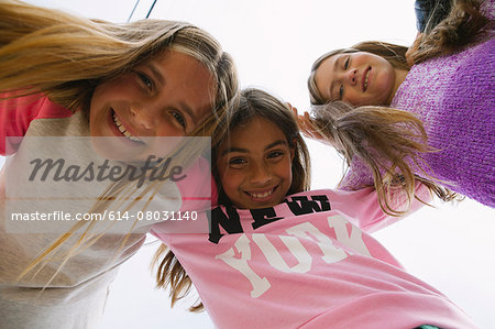 Three girls with arms round each other, low angle