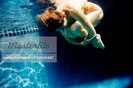 Mature woman, nude, in foetal position, underwater view