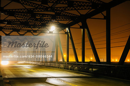 Road and silhouetted iron bridge at night, Tacoma, Washington, USA