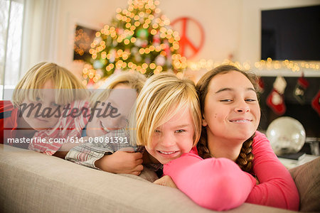 Portrait of teenage girl and brothers on sofa at christmas