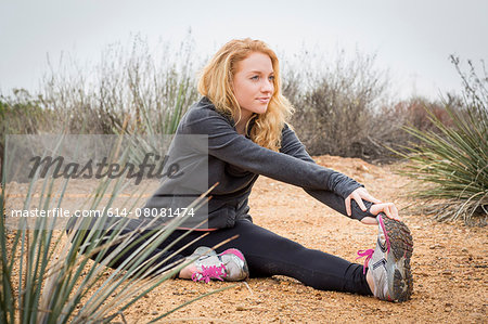 Young female runner stretching to touch toes