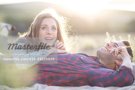 Young couple lying together chewing straw grass