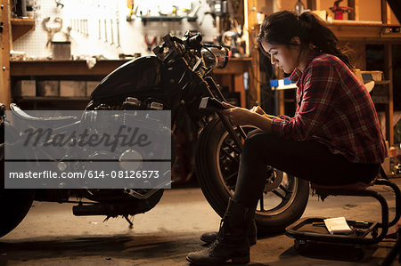 Female mechanic working on motorcycle in workshop Female mechanic working on motorcycle in workshop