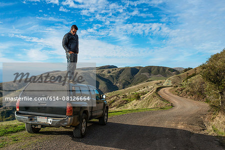 Man looking down from top of pick up truck, Big Sur, California, USA