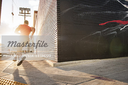 Rear view of male runner running on sidewalk Rear view of male runner running on sidewalk