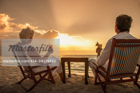 Senior couple with drinks on beach, Maldives