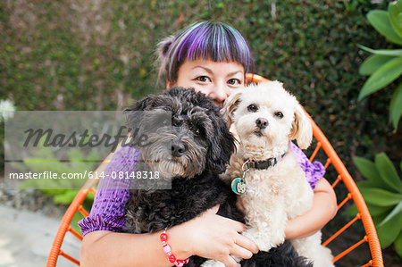 Mid adult woman sitting outdoors, hugging two dogs