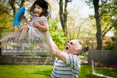 Grandfather and granddaughter playing in garden