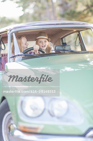 Two young girls in driving seat of car