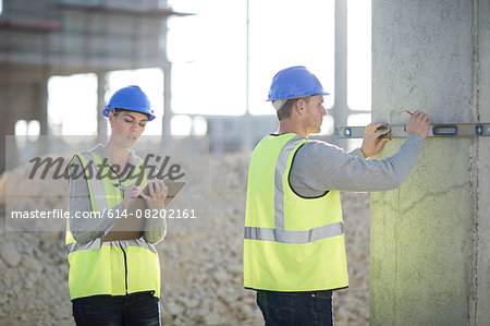 Builder using spirit level on construction site pillar