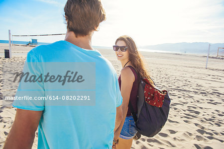 Young couple walking on beach, rear view