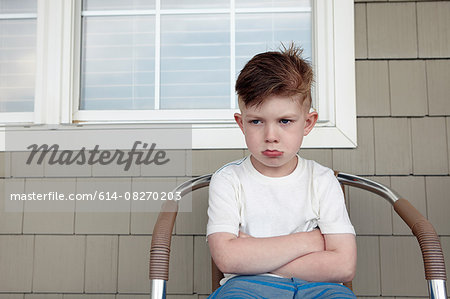 Portrait of boy sitting outside house sulking Portrait of boy sitting outside house sulking