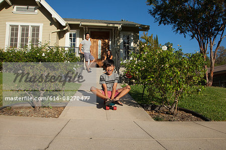 Boy skateboarding down garden path