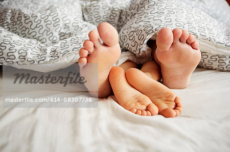 Child with bare feet in jeans. Lying on the bed. Foot barefoot