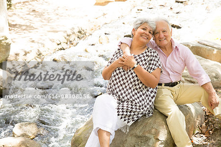 Portrait of senior couple sitting on rock, outdoors