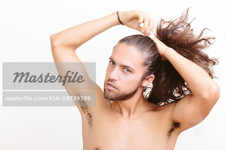 Young man with long hair, putting hair in ponytail