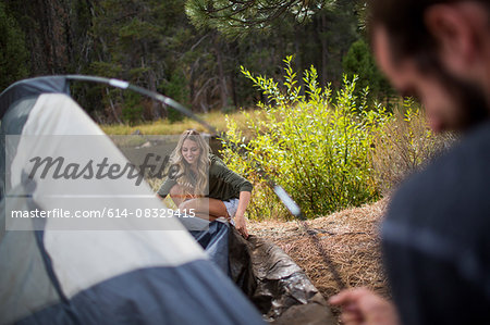 Young couple putting up tent on riverside, Lake Tahoe, Nevada, USA