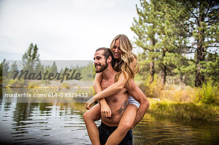 Young man giving girlfriend piggyback in river, Lake Tahoe, Nevada, USA