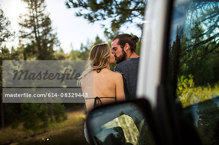 Rear view of romantic young couple kissing at riverside, Lake Tahoe, Nevada, USA