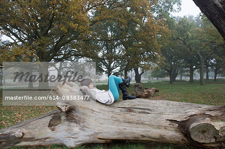 Young girl relaxing on tree stump in forest
