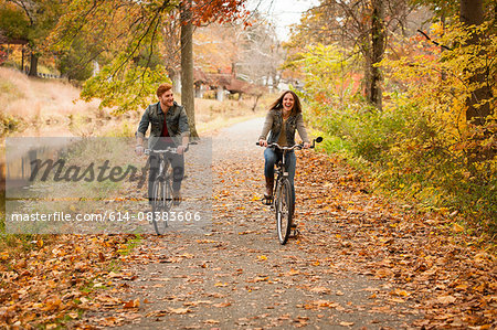 Happy young couple cycling on riverside in autumn