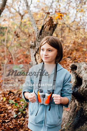 Young girl in forest, binoculars round neck