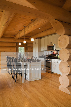 White kitchen cabinets and island and barstools in kitchen of a Scandinavian cottage style log home