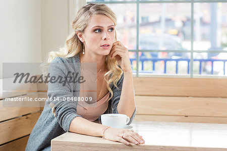 Young woman sitting at table with teacup looking away