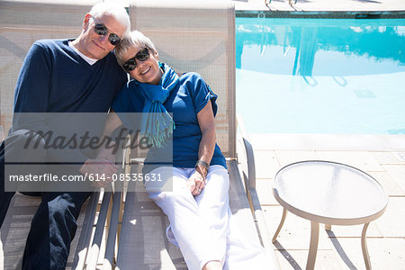 Senior couple relaxing on sun loungers beside pool