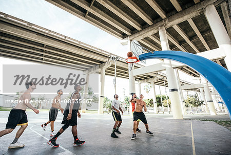 Men on basketball court watching basketball go through hoop