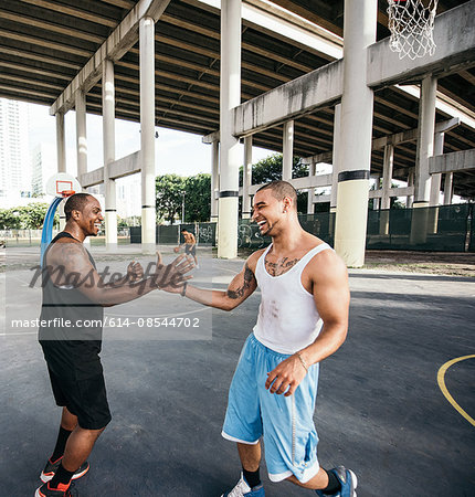 Men on basketball court shaking hand smiling