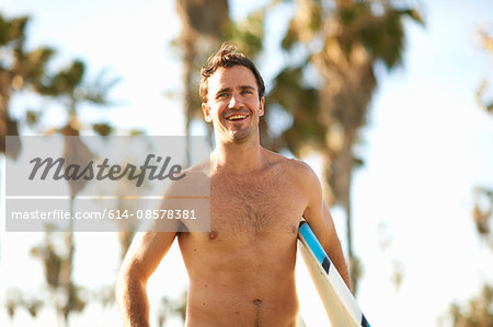 Male surfer carrying surfboard at Venice Beach, California, USA