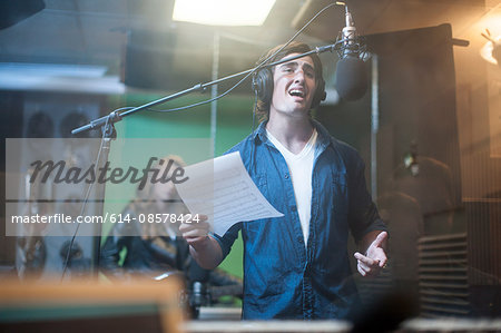 Male musician in recording studio, singing into microphone