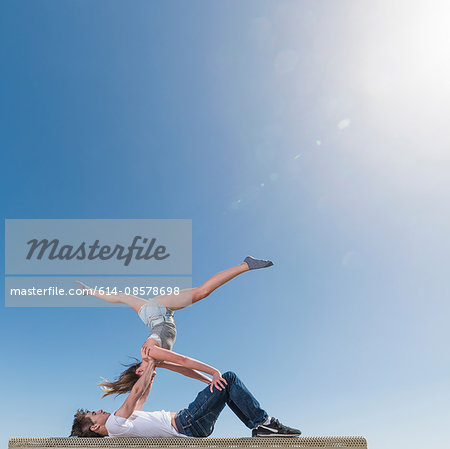 Couple practising partner yoga on bench