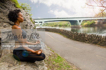 Woman sitting cross legged on rock meditating