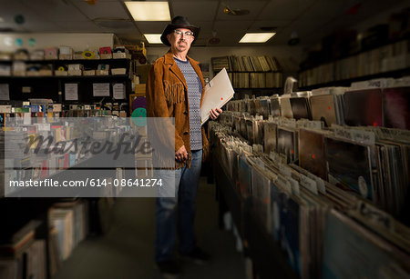 Portrait of mature man in record shop, holding records