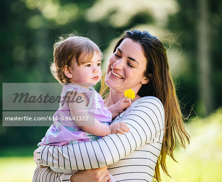 Woman carrying toddler daughter in park