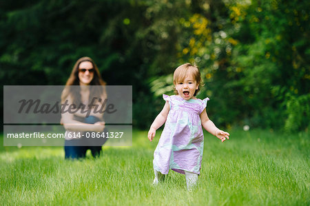 Female toddler running away from watching mother in park