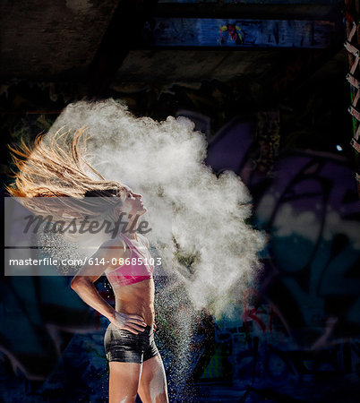 Woman standing with hands on hips throwing powder covered hair back