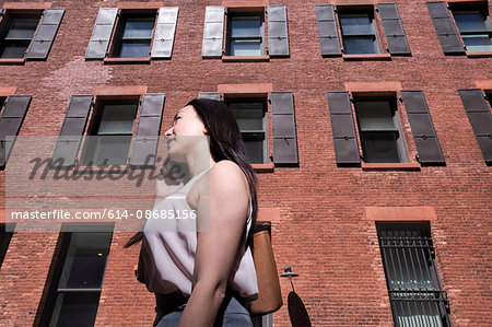 Businesswoman walking outdoors, using smartphone, low angle view