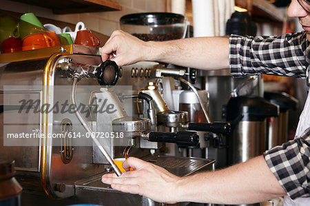 Male worker in bakery, using coffee machine, close-up