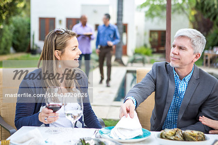 Mature man and woman talking at garden party table