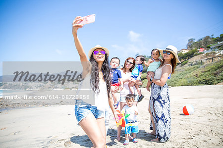 Mother taking selfie of friends and babies on beach, Malibu, California, USA Mother taking selfie of friends and babies on beach, Malibu, California, USA