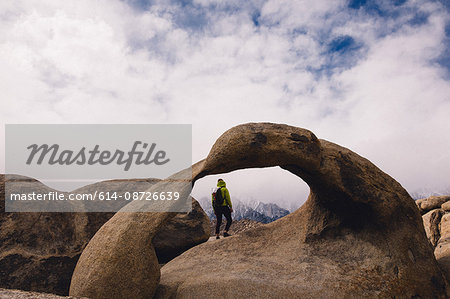 Hiker by natural rock arch, Alabama Hills, Lone Pine, California, USA